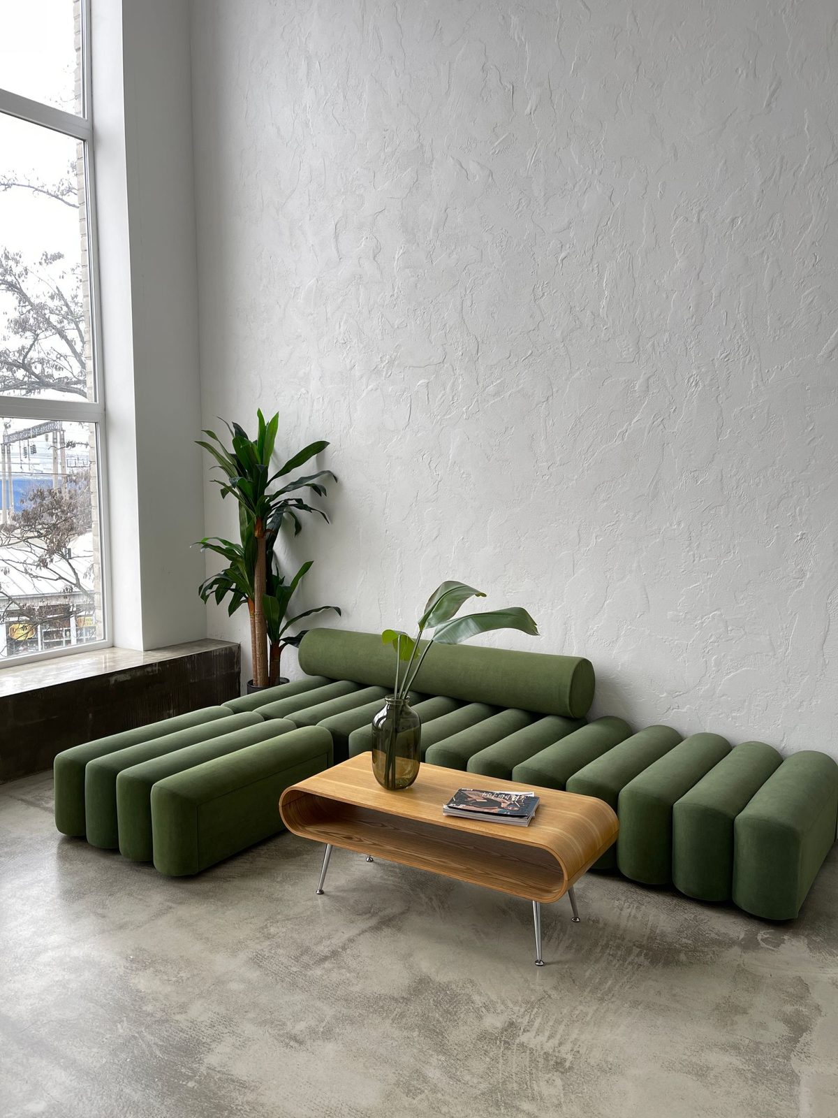 Modular olive-green sofa and timber coffee table against a textured pale wall